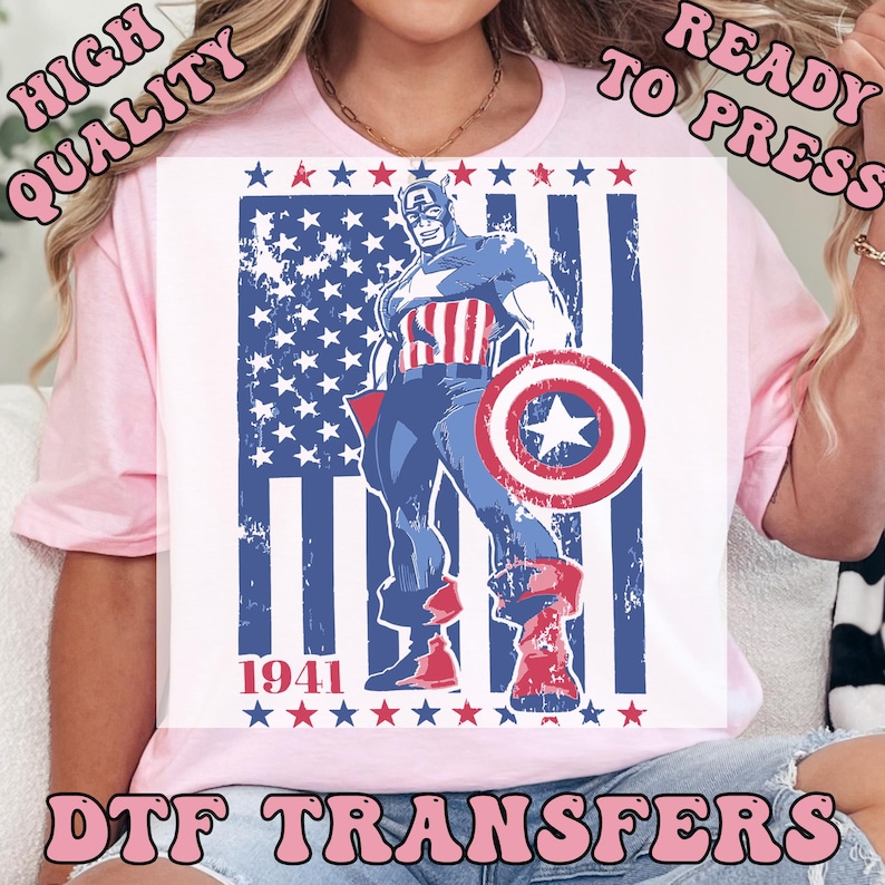 May include: A white t-shirt featuring a graphic of Captain America standing in front of a distressed American flag. The design includes the year "1941" and the text "DTF TRANSFERS", with additional text that reads "HIGH QUALITY READY TO PRESS".