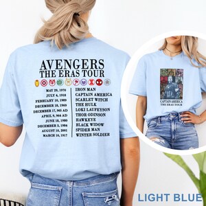 K&ouml;nnte beinhalten: Hellblaue T-Shirts mit dem Text "AVENGERS THE ERAS TOUR". Ein Shirt zeigt eine Captain America-Grafik. Auf der R&uuml;ckseite des anderen Shirts sind Daten und Charakternamen aufgef&uuml;hrt, darunter Iron Man und Spider-Man.