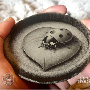 Puede incluir: Un posavasos en escala de grises con una ilustración detallada de una mariquita sobre una hoja. El posavasos tiene un borde texturizado. Las palabras "LASER TESTED" y "DIGITAL DOWNLOAD" son visibles.