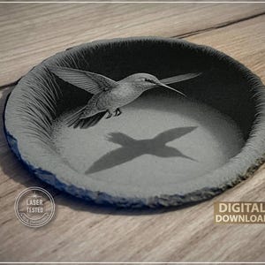 May include: A gray, circular engraved dish featuring a hummingbird in flight. The bird's shadow is visible within the dish. The words "Laser Tested" and "Digital Download" are also present.