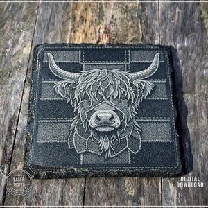 May include: A square, dark gray slate coaster with a detailed etched image of a Highland cow. The cow's face is centered, with long horns and shaggy fur. The background has a plaid pattern. The words "LASER TESTED" and "DIGITAL DOWNLOAD" are visible.