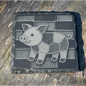 May include: A square, black slate coaster with a stitched design of a patchwork pig. The pig is gray and white, with a smiling face and a curly tail. The coaster has a rough, unfinished edge and the words "LASER TESTED" and "DIGITAL DOWNLOAD" are printed on the coaster.