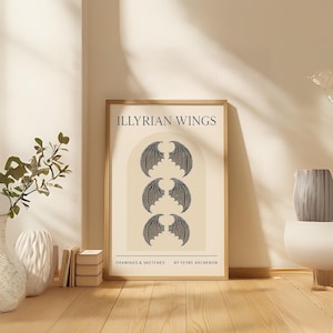Puede incluir: Una impresión artística enmarcada con el texto "ILLYRIAN WINGS" sobre tres conjuntos de alas de murciélago grises oscuras estilizadas. La obra de arte está sobre un fondo crema y enmarcada en madera clara. La parte inferior de la impresión dice "DRAWINGS & SKETCHES BY FEYRE ARCHERON."
