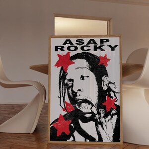 May include: A framed poster featuring a black and white image of A$AP Rocky with red star accents. The poster has the text "A$AP ROCKY" at the top. The image is in a wooden frame.