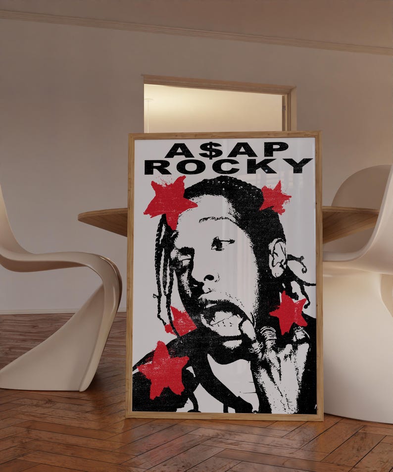 May include: A framed poster featuring a black and white image of A$AP Rocky with red star accents. The poster has the text "A$AP ROCKY" at the top. The image is in a wooden frame.