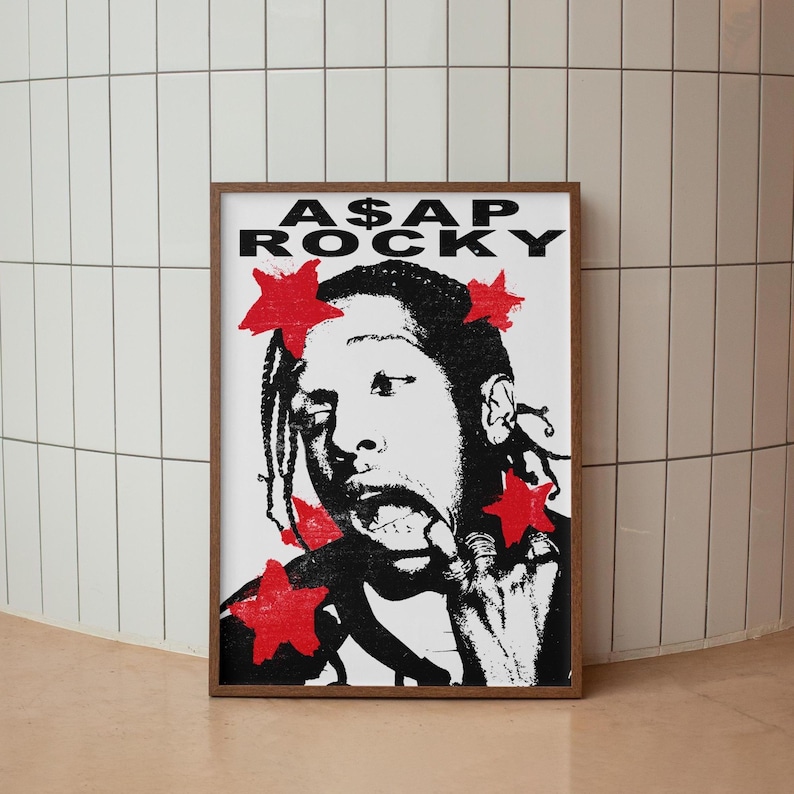 May include: A framed black and white poster featuring a stylized portrait of A$AP Rocky with red star accents. The poster has the text "A$AP ROCKY" at the top. The artwork is displayed against a white tile wall.