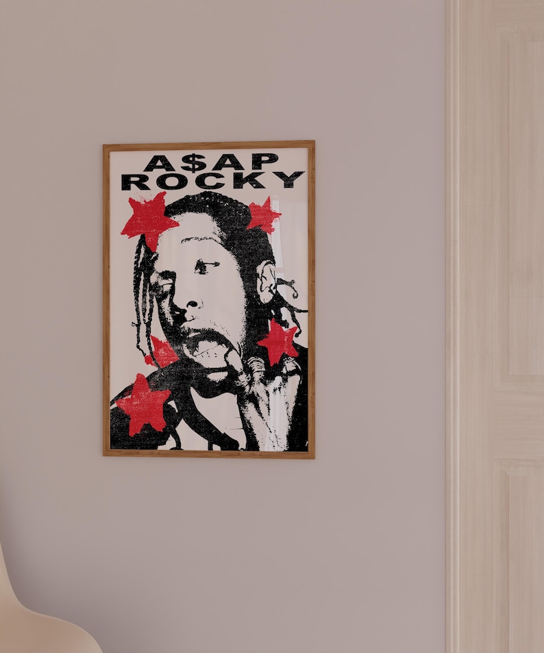 May include: A framed poster with a black and white illustration of A$AP Rocky, accented with red stars. The poster displays the text "A$AP ROCKY" in bold, black letters. The artwork is presented in a wooden frame.