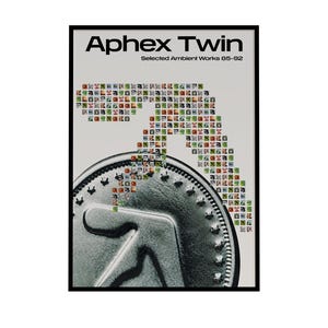 Peut inclure: A framed poster with the text "Aphex Twin" et "Selected Ambient Works 85-92." L'œuvre comprend une grande pièce de monnaie stylisée avec un motif central et une mosaïque de petits carrés colorés.
