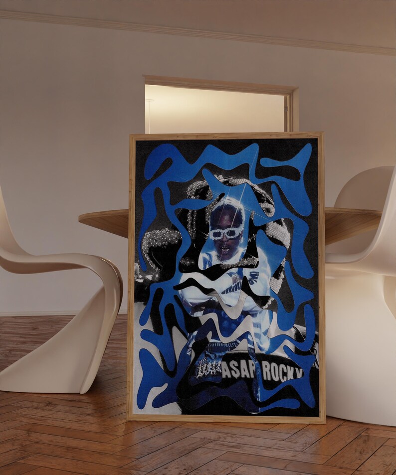 Op de afbeelding: Een ingelijste kunstdruk met een portret van een persoon met een zonnebril, bedekt met blauwe en zwarte abstracte vormen. De print heeft de tekst "ASAP ROCKY" onderaan. De lijst is van lichtgekleurd hout.