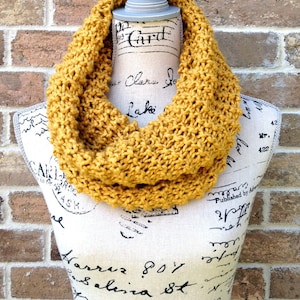 May include: A mustard yellow knitted infinity scarf. The scarf is made of a soft, chunky yarn and is perfect for keeping warm in the winter.