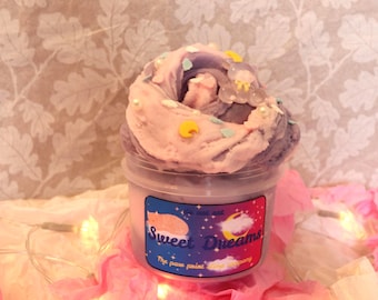 May include: A jar of colorful slime with a swirl of pink and purple. The slime is decorated with small yellow and blue embellishments. The jar has a label that reads "Sweet Dreams" with a cat and moon illustration.