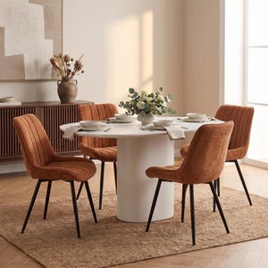 Può includere: Un set da pranzo composto da un tavolo ovale bianco con base centrale a colonna e quattro sedie imbottite in tessuto color ruggine. Ogni sedia presenta una trapuntatura verticale e sottili gambe in metallo nero. Tavola apparecchiata.
