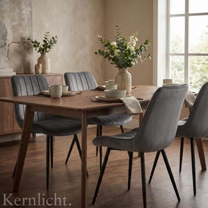 Può includere: Un set da pranzo con un tavolo rettangolare in legno e quattro sedie in velluto grigio. Il tavolo è apparecchiato con piatti, ciotole e tazze. Un vaso di fiori è al centro. Un mobile in legno è sullo sfondo.