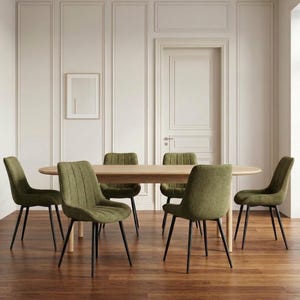 Può includere: Un tavolo da pranzo ovale in legno chiaro abbinato a sei sedie imbottite color verde oliva. Ogni sedia presenta uno schienale con cuciture verticali e quattro sottili gambe in metallo nero, offrendo un aspetto coerente attorno al tavolo.