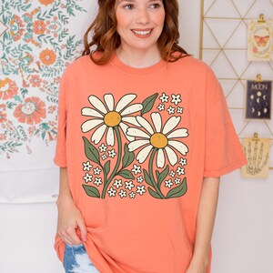 a woman standing in front of a wall with flowers on it