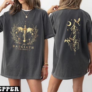 A woman wearing a grey t-shirt with a gold design on the front and back.
