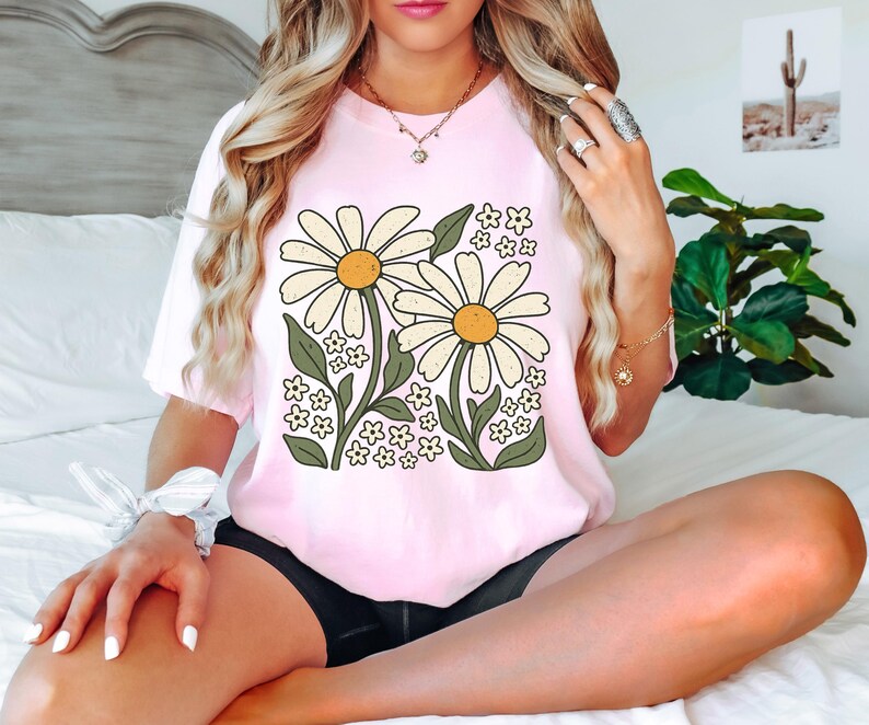 a woman sitting on a bed with a flower shirt on