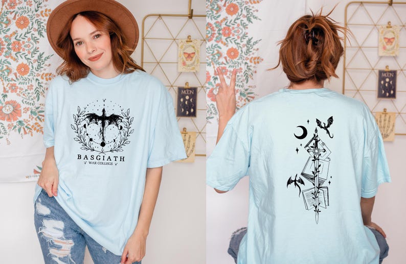A woman wearing a light blue t-shirt with a graphic design and text, posing in front of a floral background.