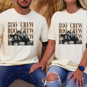 K&ouml;nnte beinhalten: Ein cremefarbenes T-Shirt mit einem Grafikdruck, der den wiederholten braunen Schriftzug "BOO CREW" und ein schwarz-wei&szlig;es Foto einer Familie in Halloween-Kost&uuml;men mit K&uuml;rbissen zeigt. Der Text "Your Name" steht in Schreibschrift dar&uuml;ber.