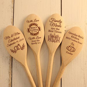 Puede incluir: Cuatro cucharas de madera con texto y diseños grabados. Una dice "Mr. & Mrs. Established September 14, 2019" con anillos. Otra dice "Mom's Cooking Est. 2005". La tercera dice "Family Meals Are the Best Times". La última dice "Grandpa Ben's Kitchen BEST Cookies Ever!"