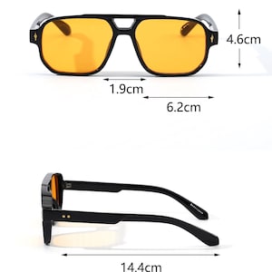 May include: Black square-framed sunglasses with orange lenses. The sunglasses measure 6.2 cm wide, 4.6 cm high, and 14.4 cm long. The frame has a bridge width of 1.9 cm. The glasses have a modern, geometric design.