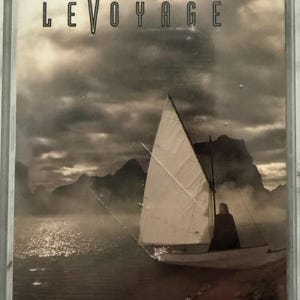 Könnte beinhalten: Kassettenhülle mit dem Album "Le Voyage" von Sandi Patti. Das Cover zeigt ein Segelboot auf dem Wasser mit bewölktem Himmel und Bergen. Der Albumtitel und der Name des Künstlers sind in fetter, serifenloser Schrift gedruckt.