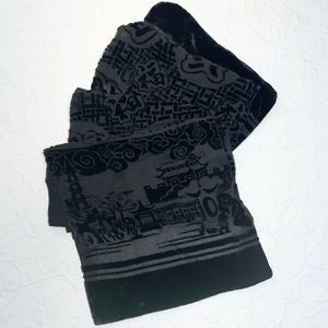 May include: A black velvet fabric piece featuring a dark gray burnout pattern depicting a traditional landscape with a pagoda, stylized clouds, and geometric motifs. The textile has a solid black border at the bottom and a soft, textured finish.