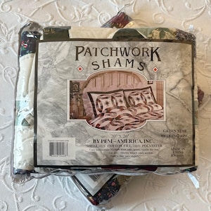 May include: A packaged set of Patchwork Shams, featuring a Green Star Wedding Ring design. The package displays a bed with matching bedding. The shams measure 20" x 26" and are made of cotton and polyester.