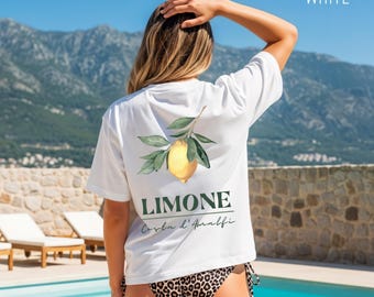 May include: White t-shirt with a lemon and leaf design on the back, with the word "LIMONE" and "Corba d'Amalfi" printed below. The model is wearing a leopard print bikini bottom. The word "WHITE" is printed in the upper right corner.
