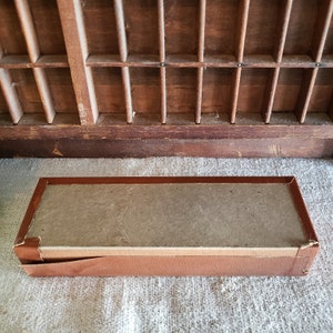 May include: A brown cardboard box with a brown leather trim. The box is empty and has a textured surface.