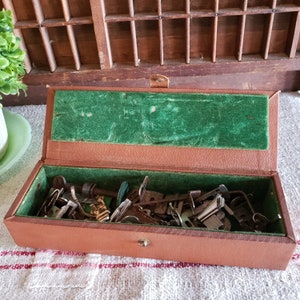 May include: A brown leather sewing box with a green felt lining. The box is open and filled with various sewing tools and needles.