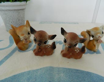 May include: Four vintage ceramic figurines: two squirrels and two deer. The squirrels are orange and cream-colored, with curled tails. The deer are brown with white spots and black ears. The figurines are on a patterned surface.