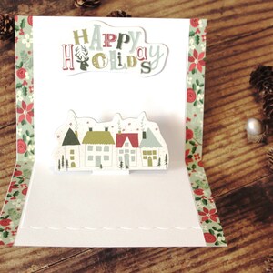 Tarjeta navideña emergente l Estilo escandinavo l Pueblo navideño l Felices fiestas l Rojo, verde y blanco l Única l Interior en blanco