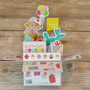 Tarjeta de cumpleaños 3D desplegable l Divertida y brillante l Azul, amarillo y rosa l Globos de payaso con forma de animalitos para cupcakes l Se pliega para enviar por correo l Envío gratuito a EE. UU.