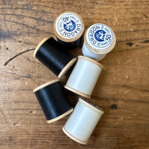 May include: Four spools of thread, two black and two white, with labels that say "Dragon Cord 60 Three 40 yds" and "Dragon Cord 60 Three 50 yds".