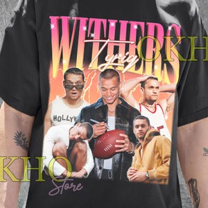 May include: Black unisex t-shirt featuring a graphic of several men with the text "WITHERS Lyric" in a gradient pink and yellow font. The shirt also has the text "Unisex T-Shirt".