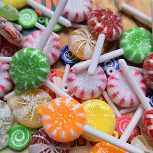 May include: A collection of colorful candy lollipops with white sticks. The lollipops have a variety of designs, including swirls, stripes, and polka dots.