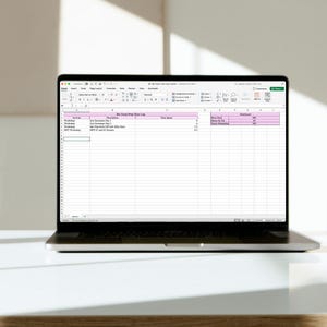 Op de afbeelding: Een zwarte laptop met een spreadsheet met de titel "Our Team Prep Hour Log" op een wit oppervlak. De spreadsheet heeft kolommen voor activiteit, tijdsduur en uren. De laptop is open en toont een gedetailleerd overzicht van de gegevens.