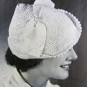 May include: A white crocheted hat with a large bow on top. The hat is made with a delicate stitch and has a scalloped edge.