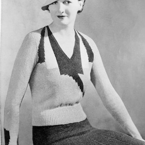 May include: A monochrome image of a woman in a knitted outfit, including a sweater with a V-neck and a geometric pattern, and a skirt. She is also wearing a hat. The photograph has a vintage aesthetic.