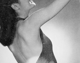 Pode incluir: Uma fotografia a preto e branco de uma mulher a usar um top de malha sem mangas com decote halter. O top é de malha canelada e tem um fecho de botão nas costas.