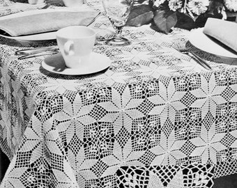 May include: A white crocheted tablecloth with a delicate floral pattern. The tablecloth is laid on a table with white dishes and glasses, and a bouquet of white flowers is in the background.