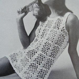 May include: A white crochet dress with a sleeveless design. The dress has a delicate, openwork pattern and a loose, flowing silhouette.