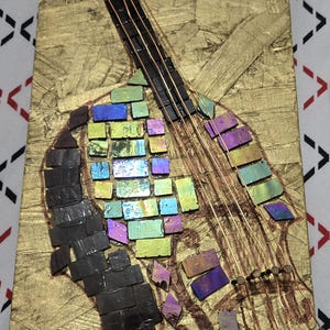 May include: A mosaic art piece depicting a guitar on a gold-colored background. The guitar's body is composed of iridescent tiles in shades of blue, green, and purple. The neck and strings are represented with dark lines and copper wire.