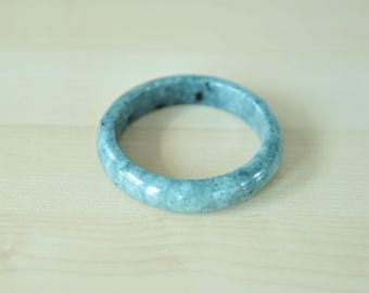 May include: A light blue jade bangle bracelet with a mottled pattern.