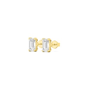 May include: A pair of gold stud earrings with emerald-cut, clear gemstones. The earrings are set in a gold bezel setting and have a post and butterfly backing. The earrings are displayed on a white background.