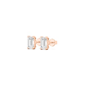 May include: A pair of rose gold stud earrings. Each earring features a rectangular, clear gemstone set in a four-prong setting. The earrings are displayed on a white background.