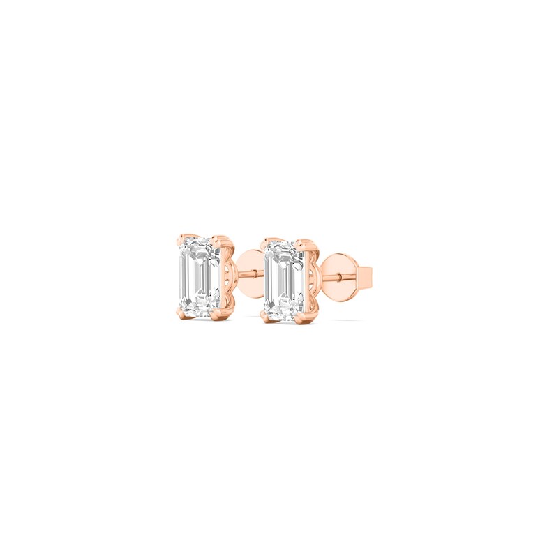 May include: A pair of rose gold stud earrings. Each earring features a rectangular, clear gemstone set in a four-prong setting. The earrings are displayed on a white background.