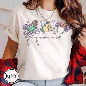 May include: A white ceramic mug with a black handle and the text "But First, Coffee" in a bold, black font. The mug is set against a neutral background, highlighting its simple design.