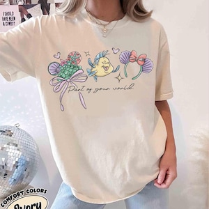 May include: A white ceramic mug with a black handle and the text "But First, Coffee" in a bold, black font. The mug is set against a blurred background, suggesting a cosy setting.